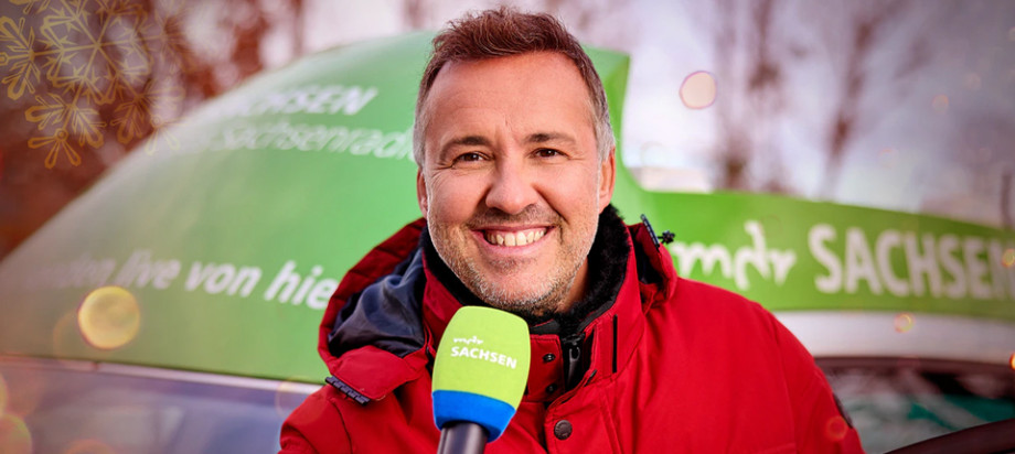 Silvio Zschage hält ein Mikrofon und lächelt in die Kamera.